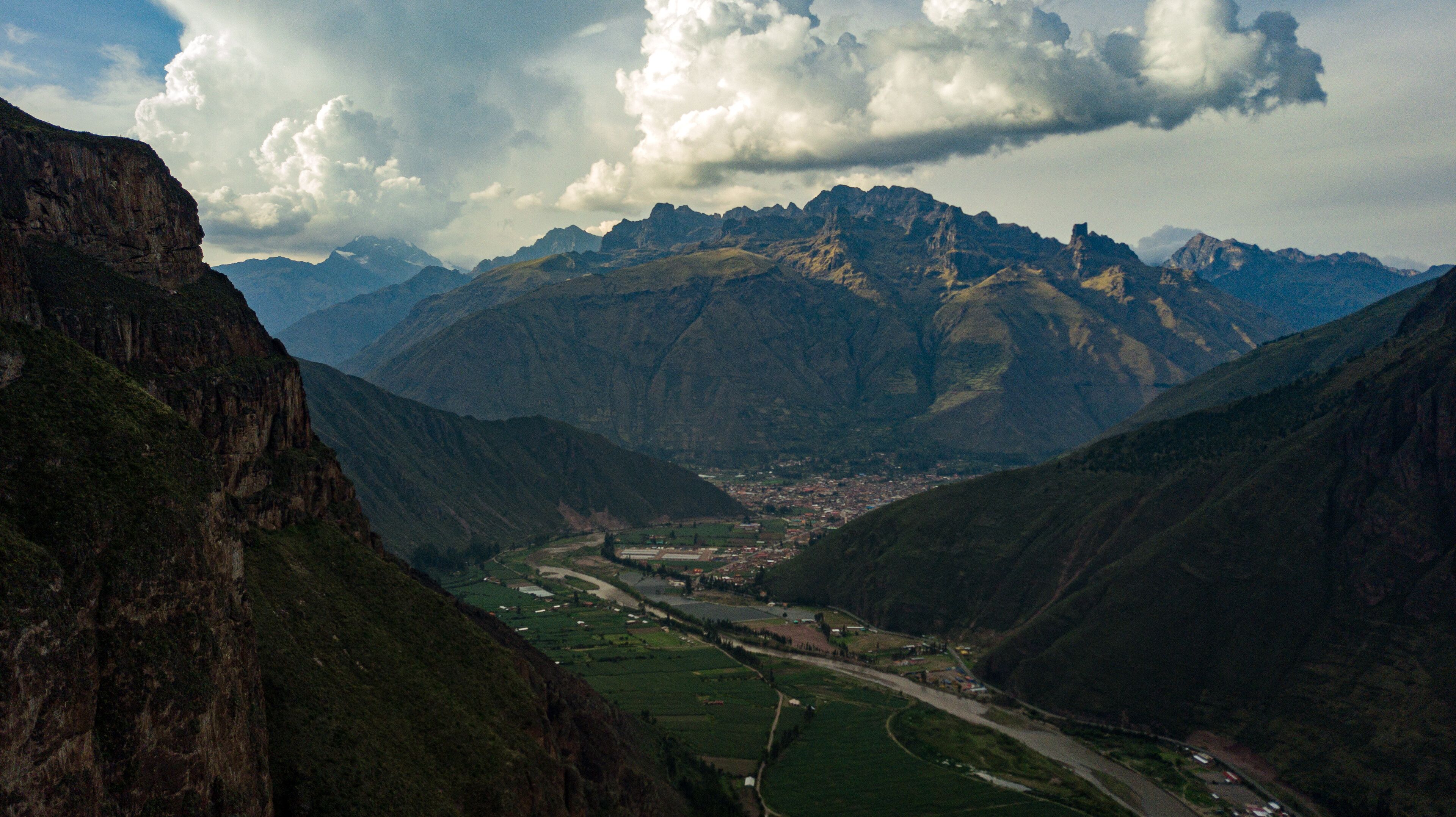 Aerial view on town located in Sacred Valley of Incas in Cusco, Peru. Mountains surrounding the river basin and towns with clouds