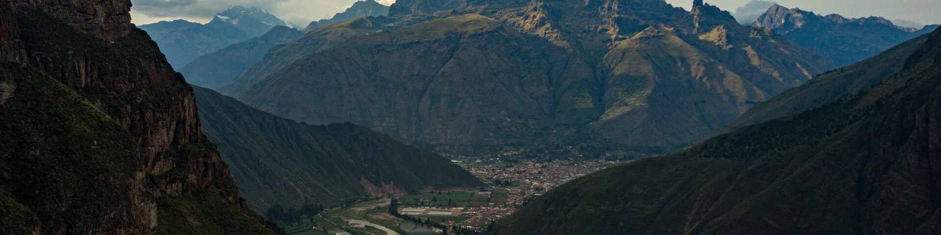 A valley with a river, surrounded by mountains and a town.