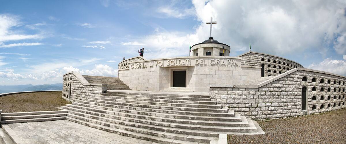 A stone monument with steps leading up to it, a dome, and a cross on top.
