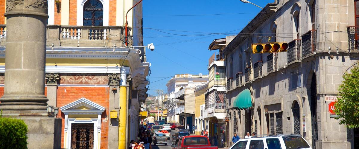A busy urban street lined with historic buildings, traffic lights, and pedestrians.