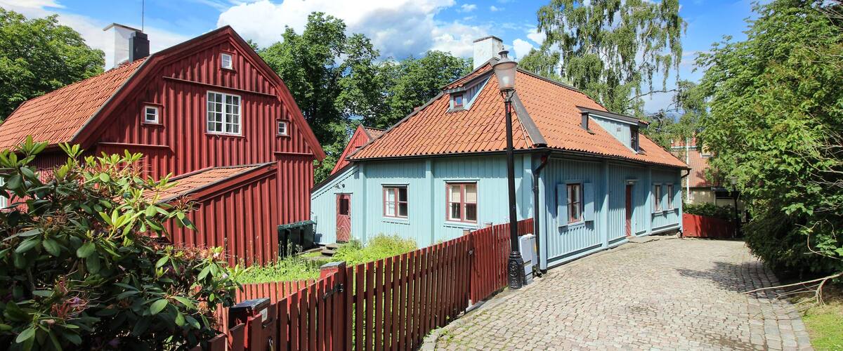 A cobblestone path leading to two traditional houses with red and blue exteriors.
