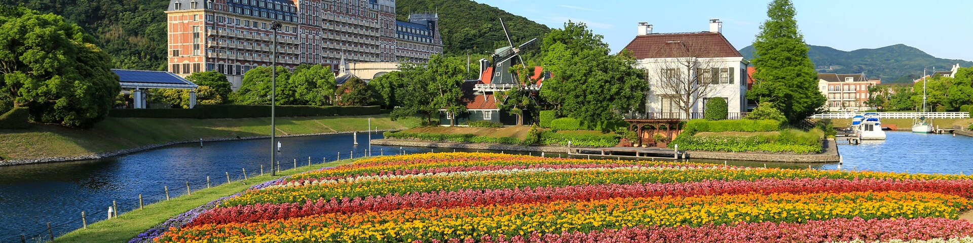Um hotel grande com uma torre, um rio e um jardim de flores.