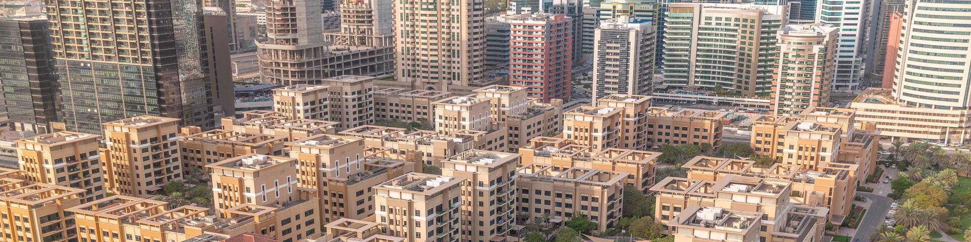 Low rise buildings in Greens district and skyscrapers in Barsha Heights district aerial timelapse. Dubai skyline