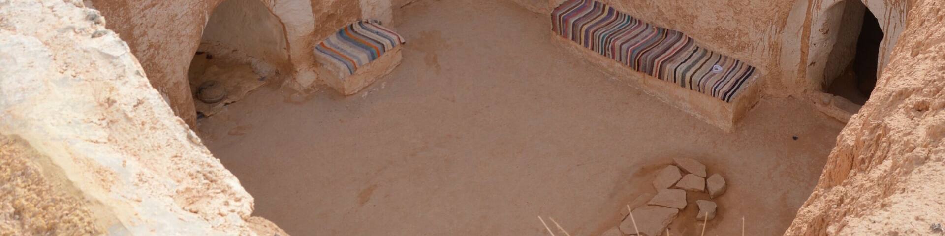 Underground Troglodyte house inner yard in Tunisia, Africa, rooftop Yellow sand, brown earthen and white plastered walls