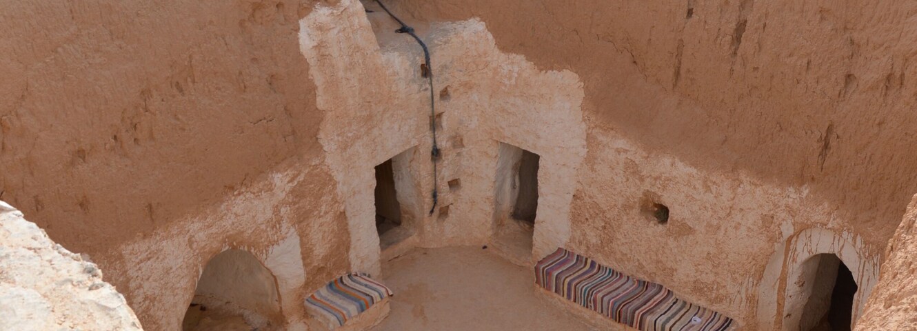 Underground Troglodyte house inner yard in Tunisia, Africa, rooftop Yellow sand, brown earthen and white plastered walls