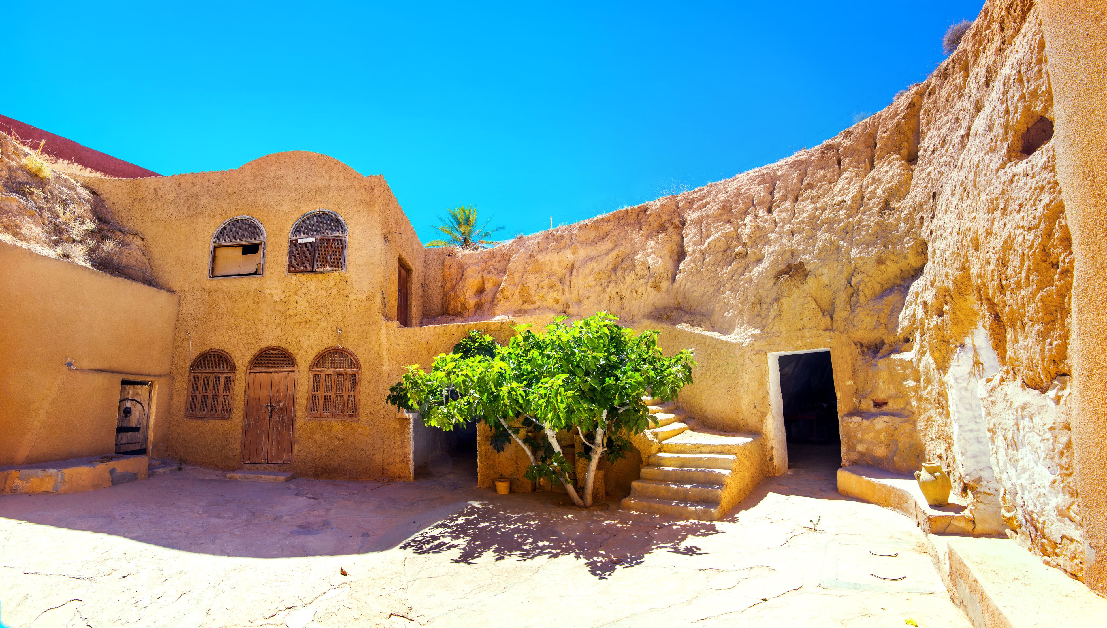 A courtyard with traditional architecture, including arched windows and a tree in the center.