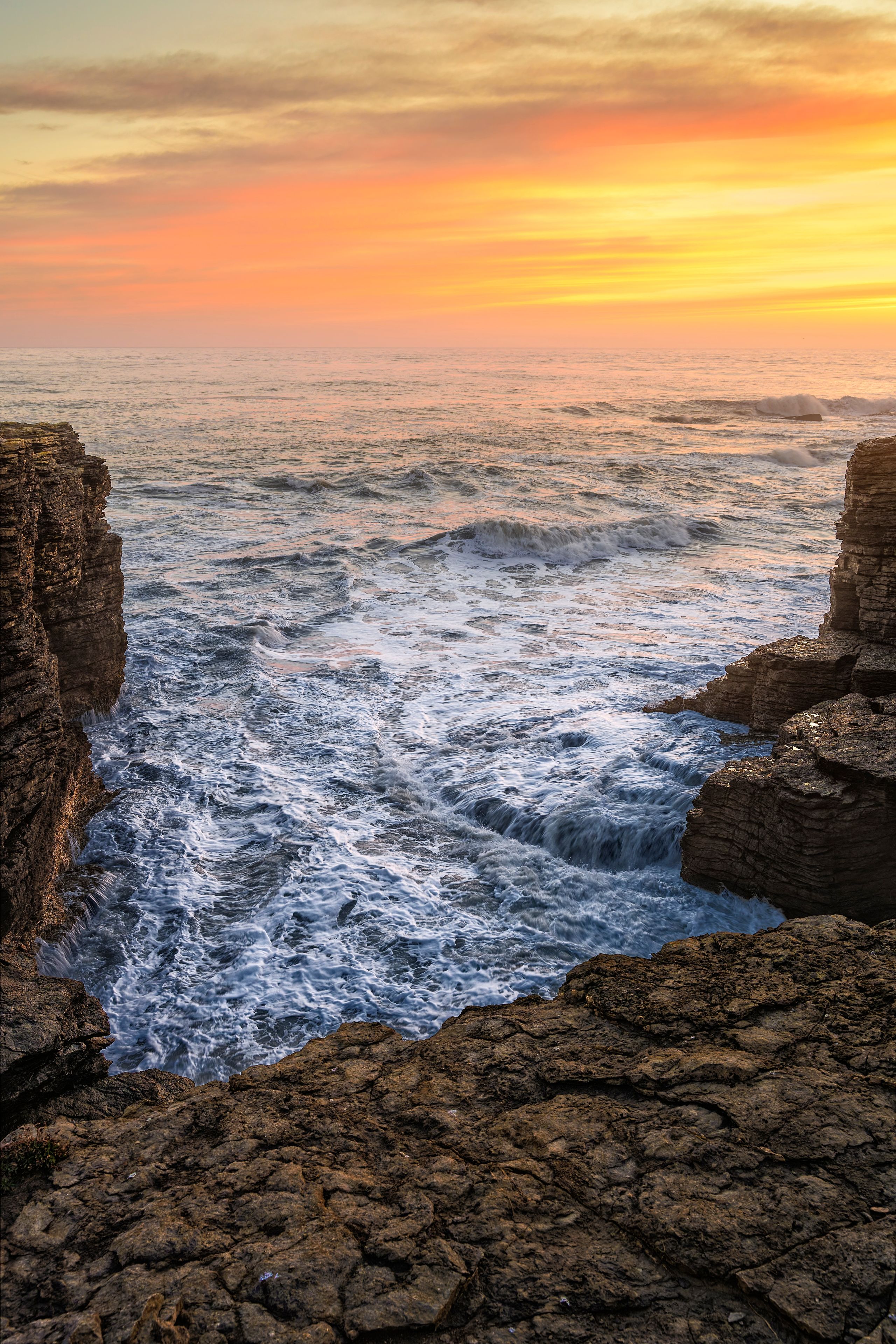 A coastal landscape with rocky cliffs and turbulent ocean waves.