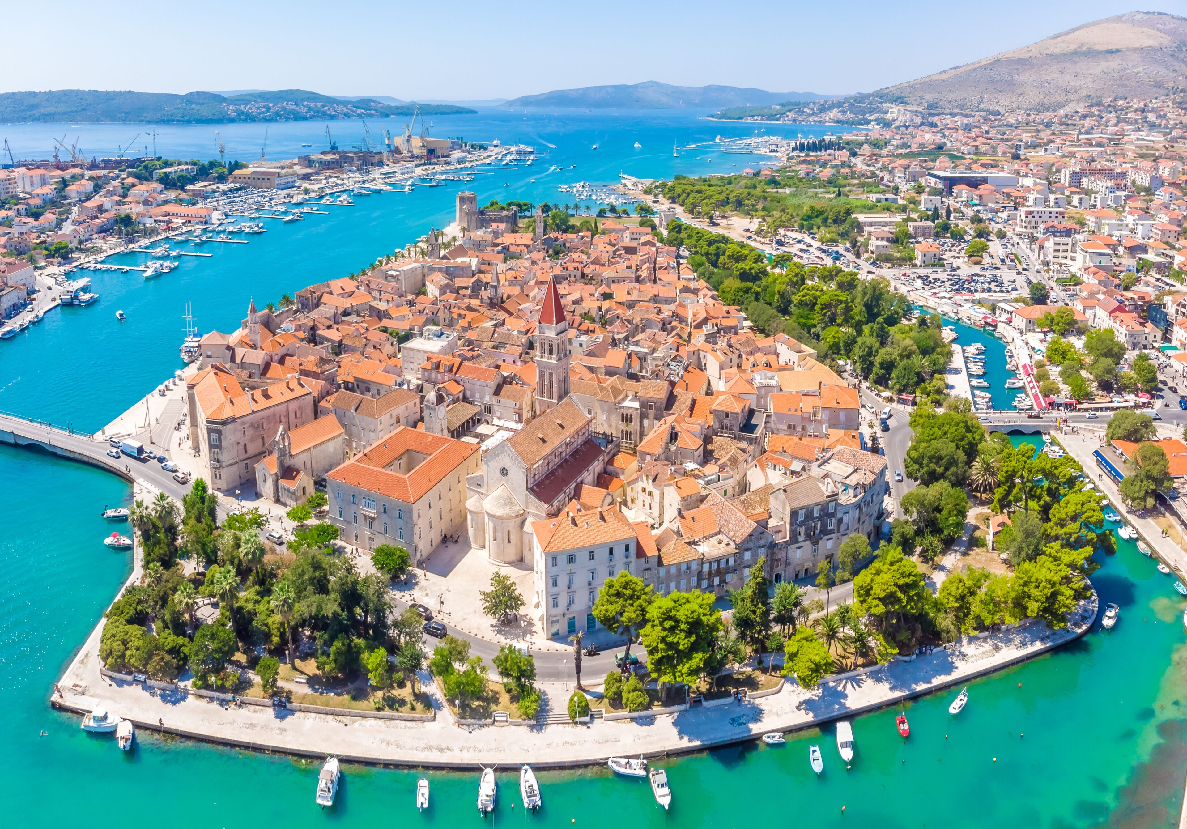A coastal city with a historic center, harbor, and surrounding greenery.
