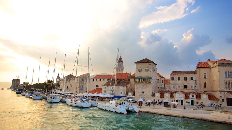 A harbor with boats docked, a prominent tower, and historic buildings with red roofs.