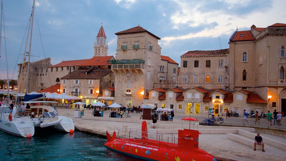 A harbor with boats, a red submarine, and historic buildings.