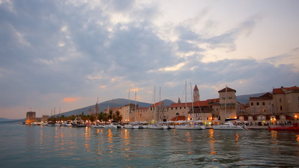 A harbor with boats, historic buildings, and a mountainous backdrop.