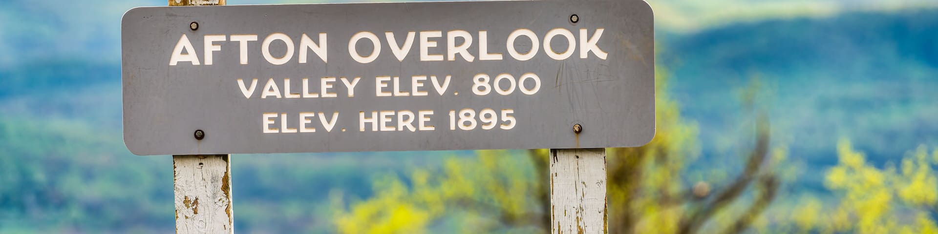 Overlook sign text for Afton valley and elevation at Blue Ridge parkway appalachian mountains in summer with nobody and scenic lush foliage bokeh background