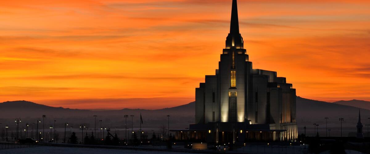 A church with a tall spire against a sunset sky.