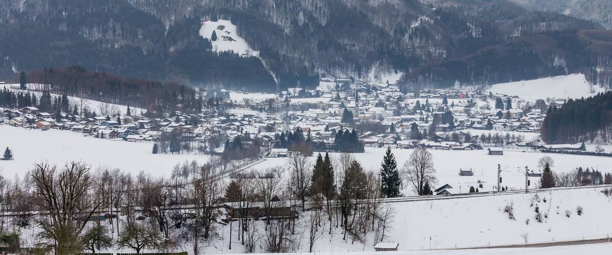 A snow-covered town nestled in a valley with mountains in the background.