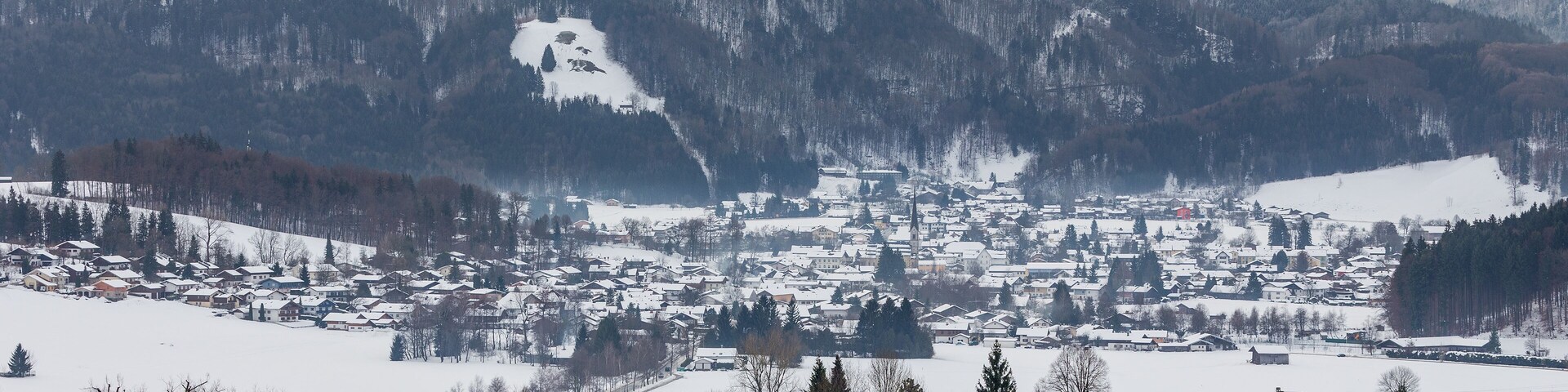 A snow-covered town nestled in a valley with mountains in the background.