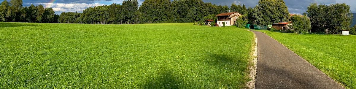 A lush green field with a rainbow arching over a rural landscape.