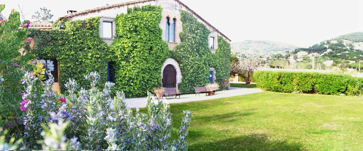 A building covered in ivy, a well-maintained lawn, and a mountainous landscape in the background.