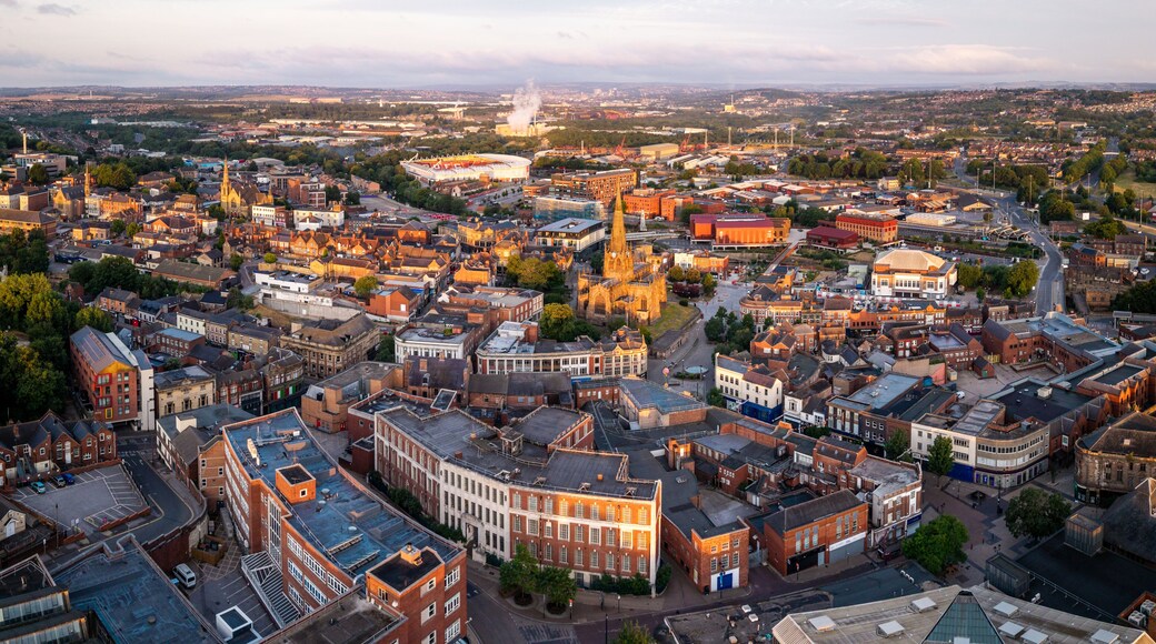 A panoramic view of a cityscape with a prominent cathedral, a large stadium, and dense urban buildings.