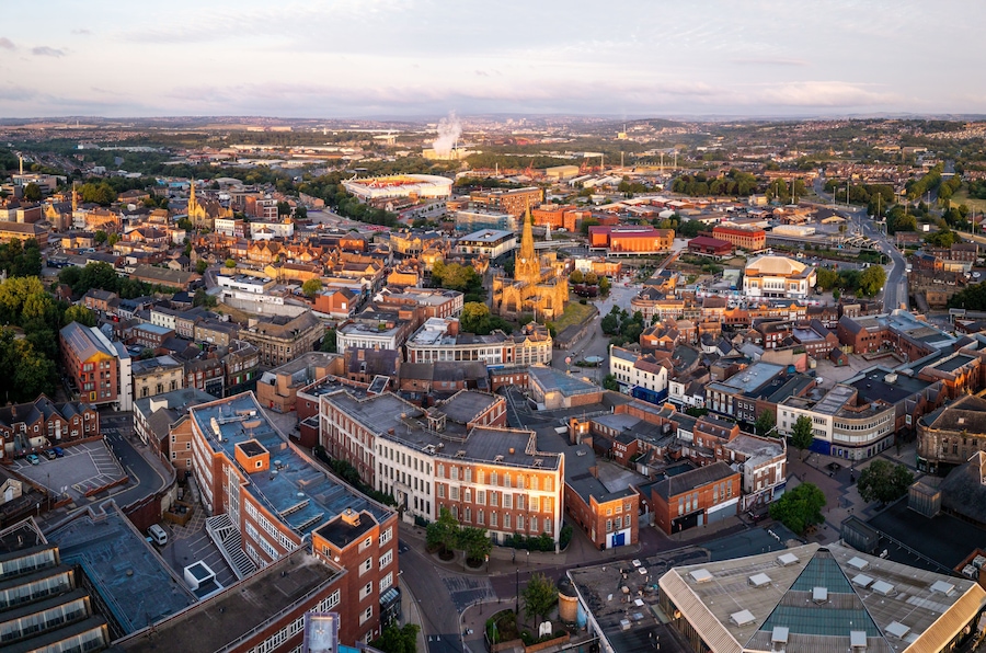 A panoramic view of a cityscape with a prominent cathedral, a large stadium, and dense urban buildings.