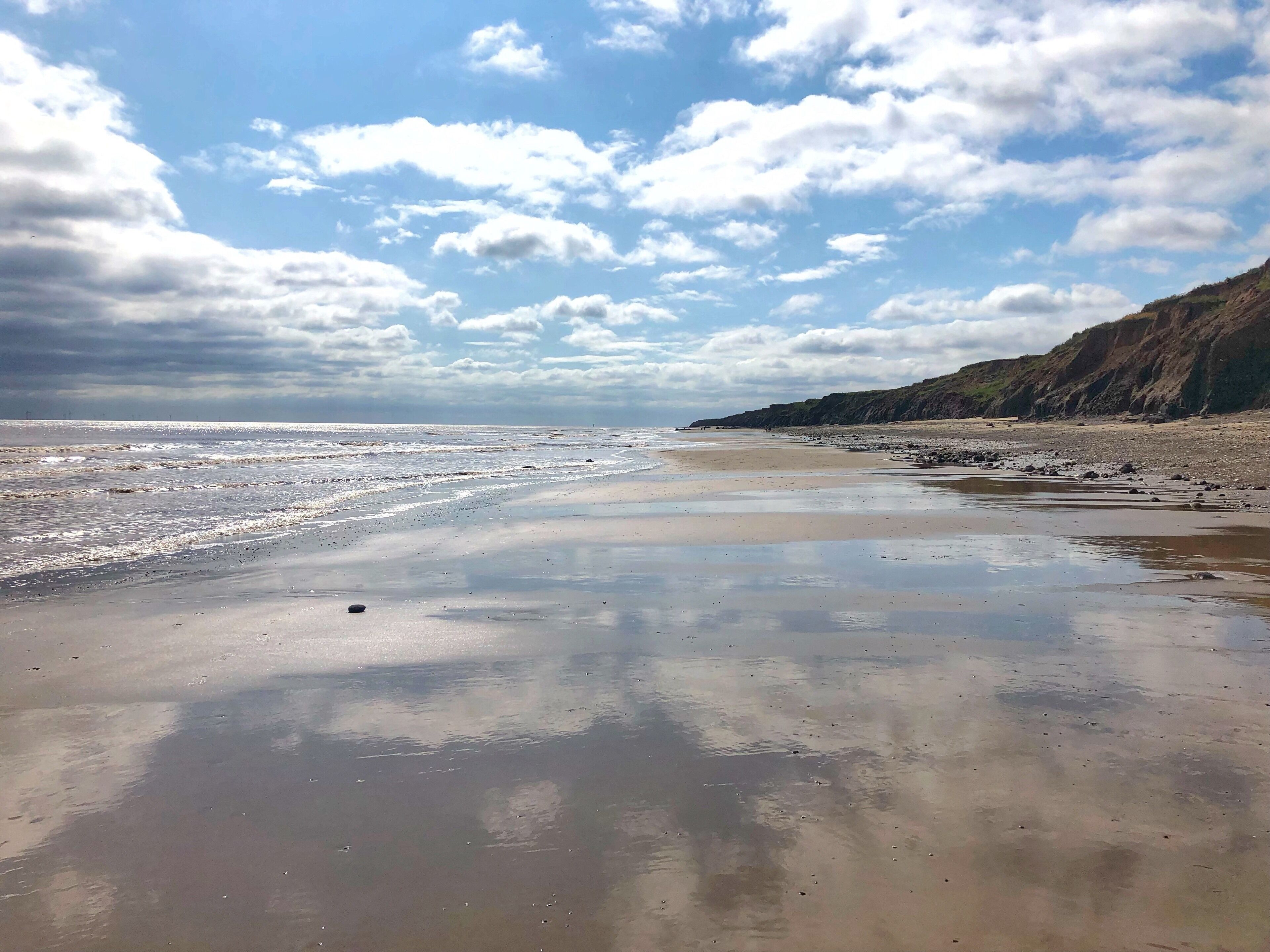 Ein Strand mit blauem Himmel und sanften Wellen.