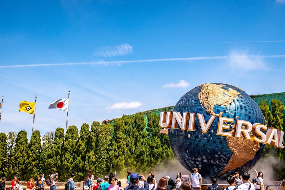 A large globe with the word "UNIVERSAL" on it, surrounded by palm trees and flags.