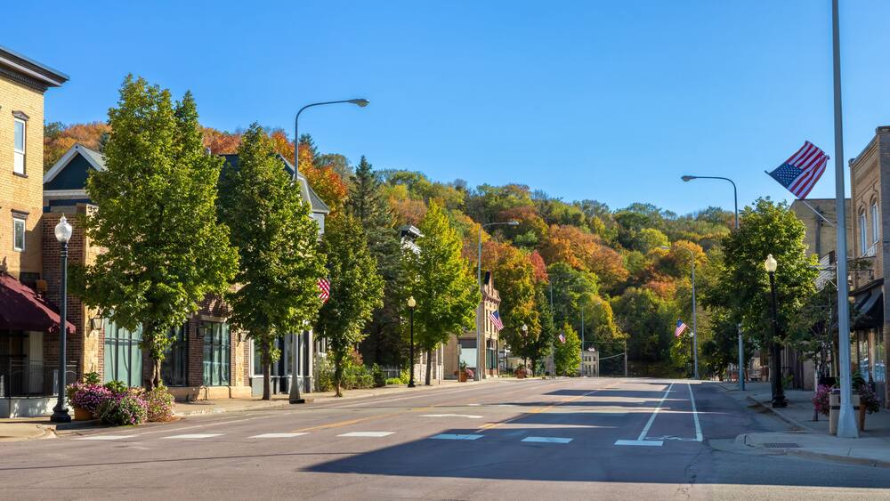 Eine von Bäumen gesäumte Straße mit amerikanischen Flaggen, Gebäuden und Herbstlaub.