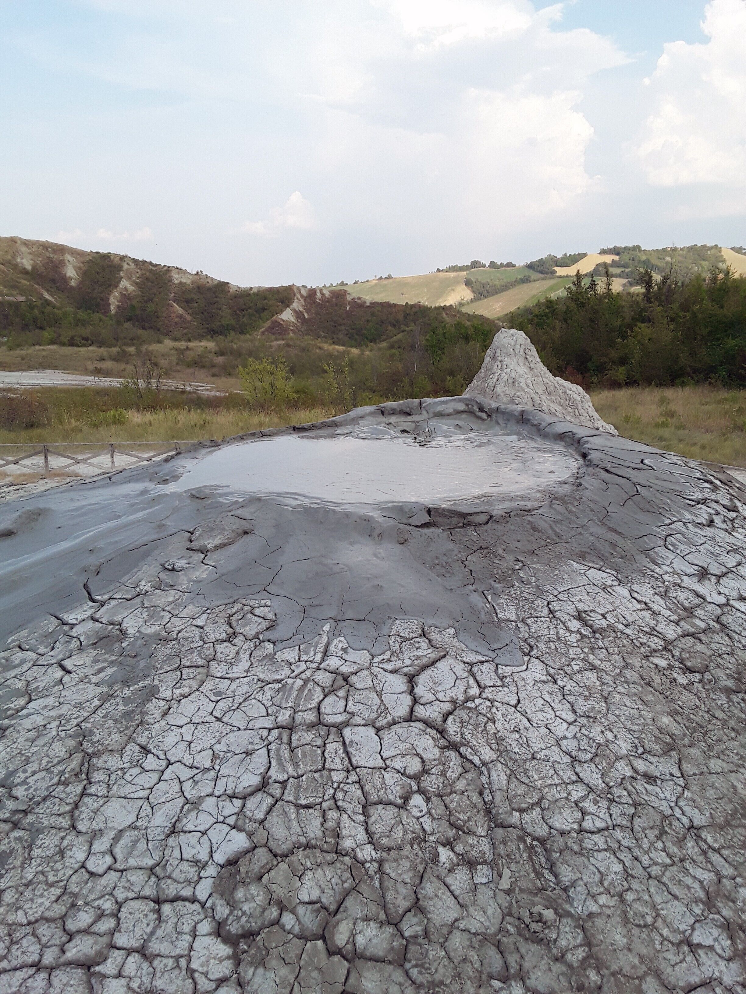 A dry, cracked landscape with a mound of earth in the center.