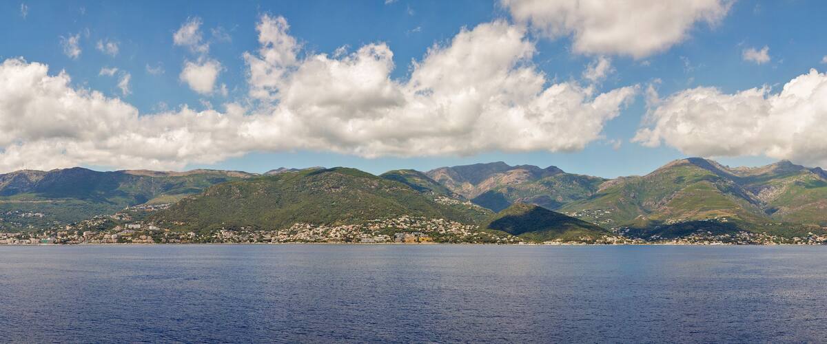 A coastal town with mountains in the background and a clear sky.