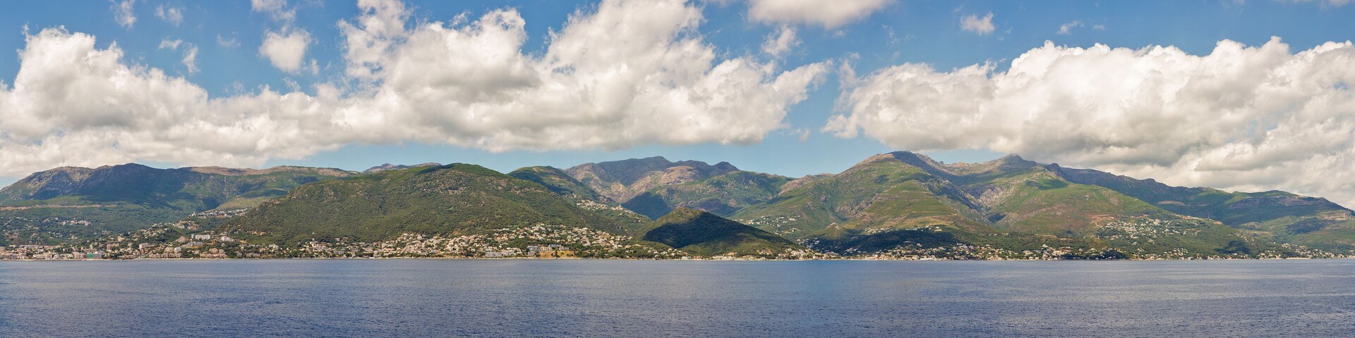 A coastal town with mountains in the background and a clear sky.