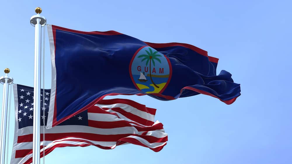 Flag of Guam waving in the wind with the US flag on a clear day