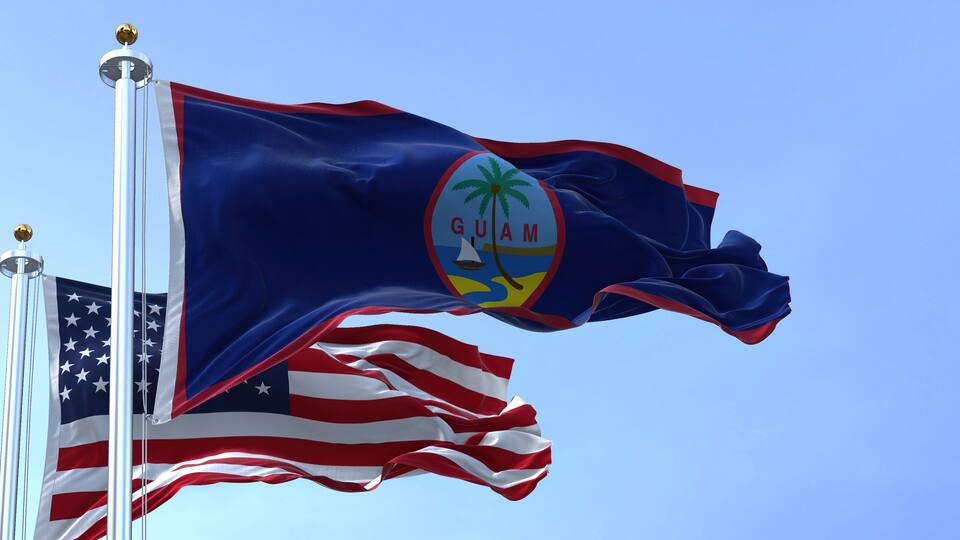 Flag of Guam waving in the wind with the US flag on a clear day