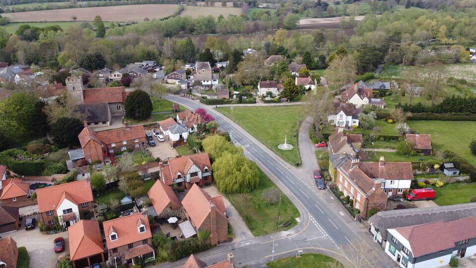 A rural village with houses, a main road, and surrounding fields.