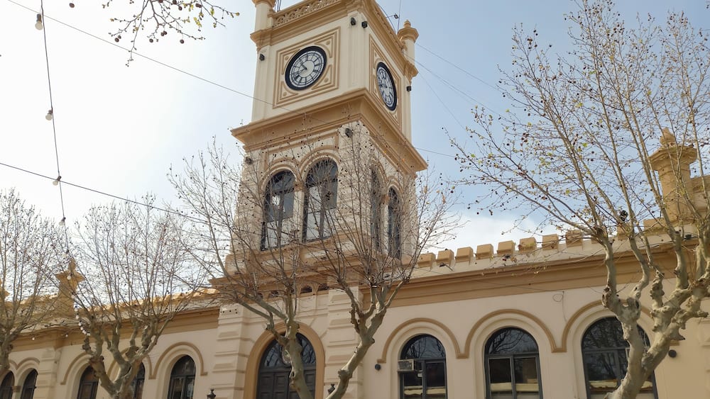 Un bâtiment historique doté d’une tour horlogée, de fenêtres en arc de cercle et d’une porte centrale.