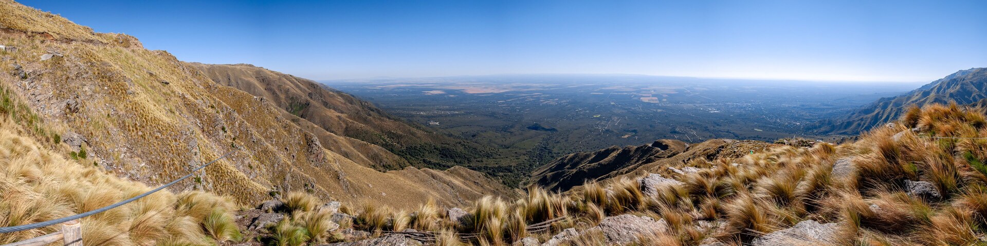 A mountainous landscape with a clear view of a valley and distant cityscape.