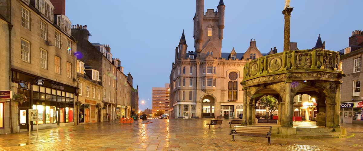 A historic square with a prominent tower, a decorative fountain, and traditional buildings.
