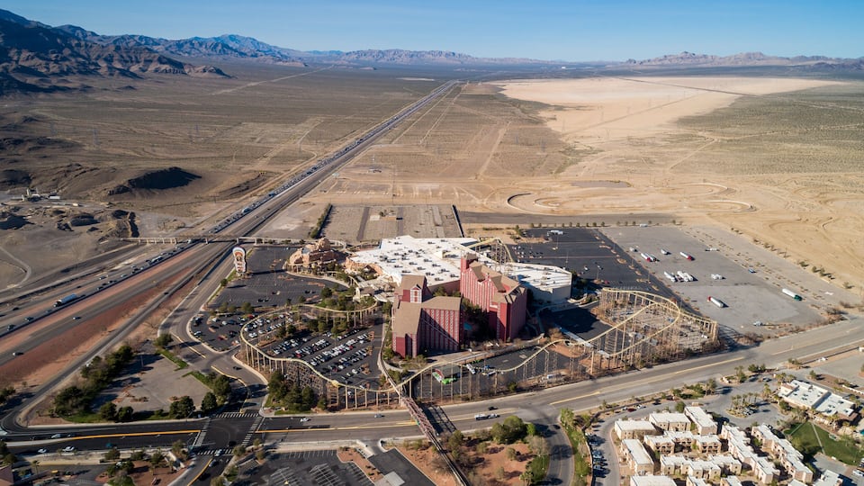 An aerial view of a desert landscape with a large building complex, roads, and a parking area.