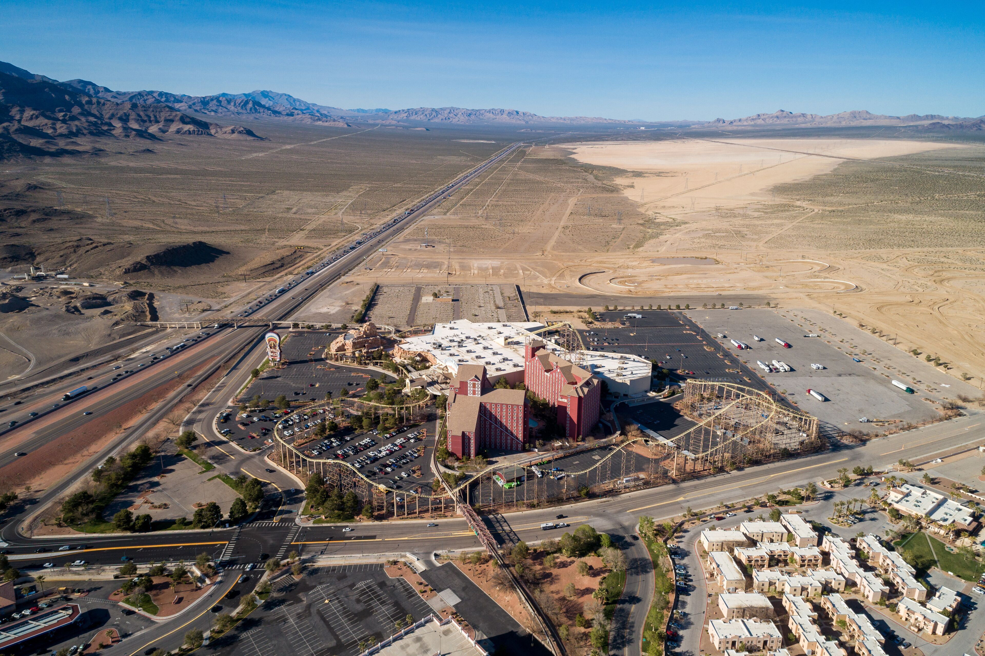 An aerial view of a desert landscape with a large building complex, roads, and a parking area.