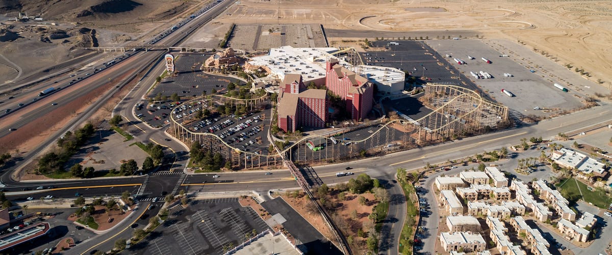 An aerial view of a desert landscape with a large building complex, roads, and a parking area.