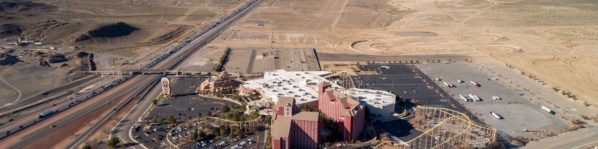 An aerial view of a desert landscape with a large building complex, roads, and a parking area.