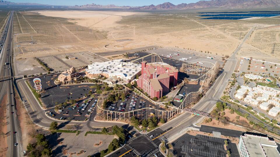 An aerial view of a parking lot, a red building, and a mountainous landscape.