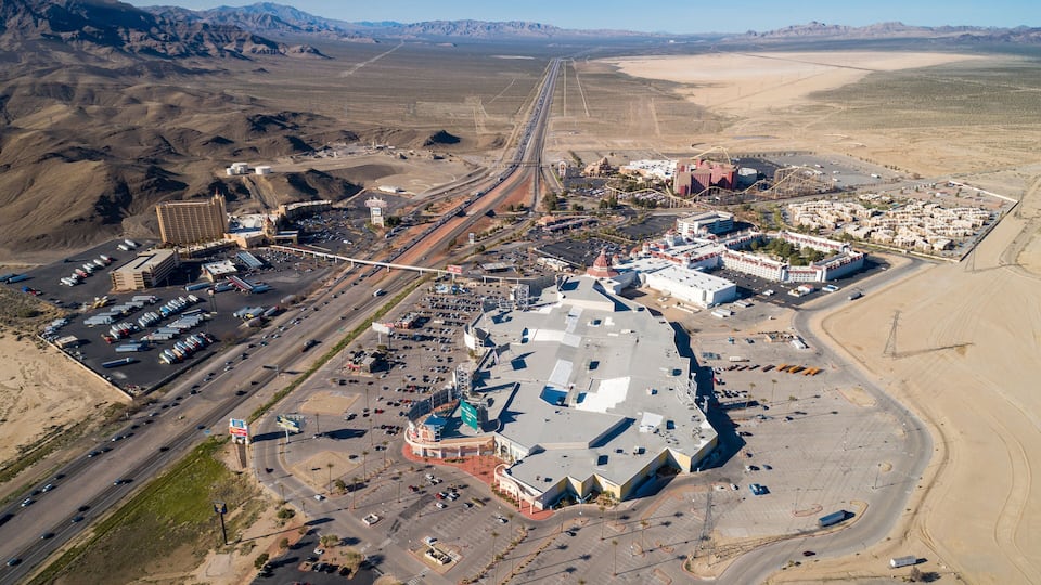 An aerial view of a desert city with a prominent highway, a large stadium, and a casino complex.