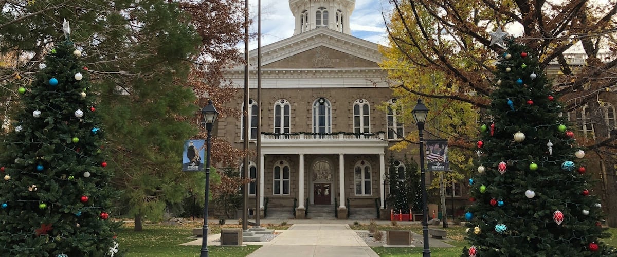 A building with a dome and columns, flanked by two decorated Christmas trees.