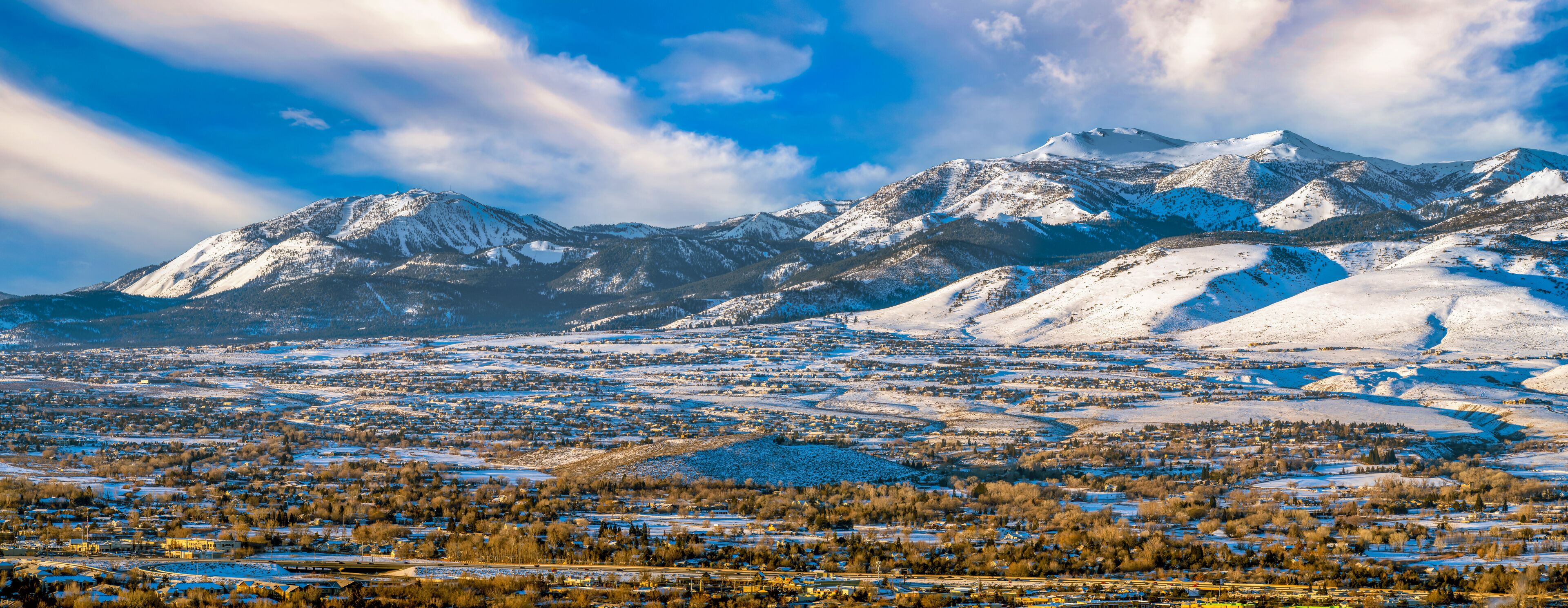 A snow-covered mountain range with a town in the foreground.