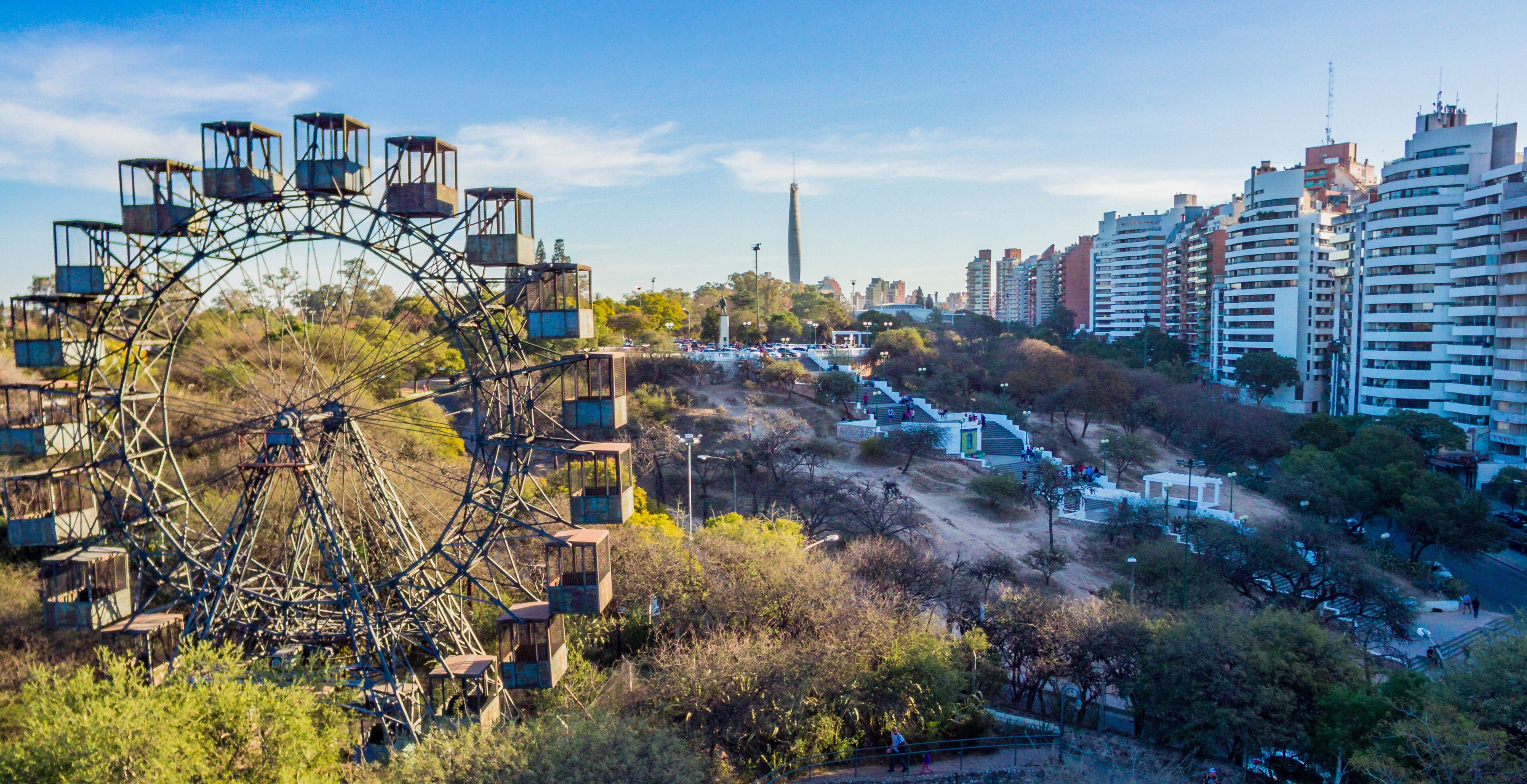 A Ferris wheel, a tall monument, and modern high-rise buildings.
