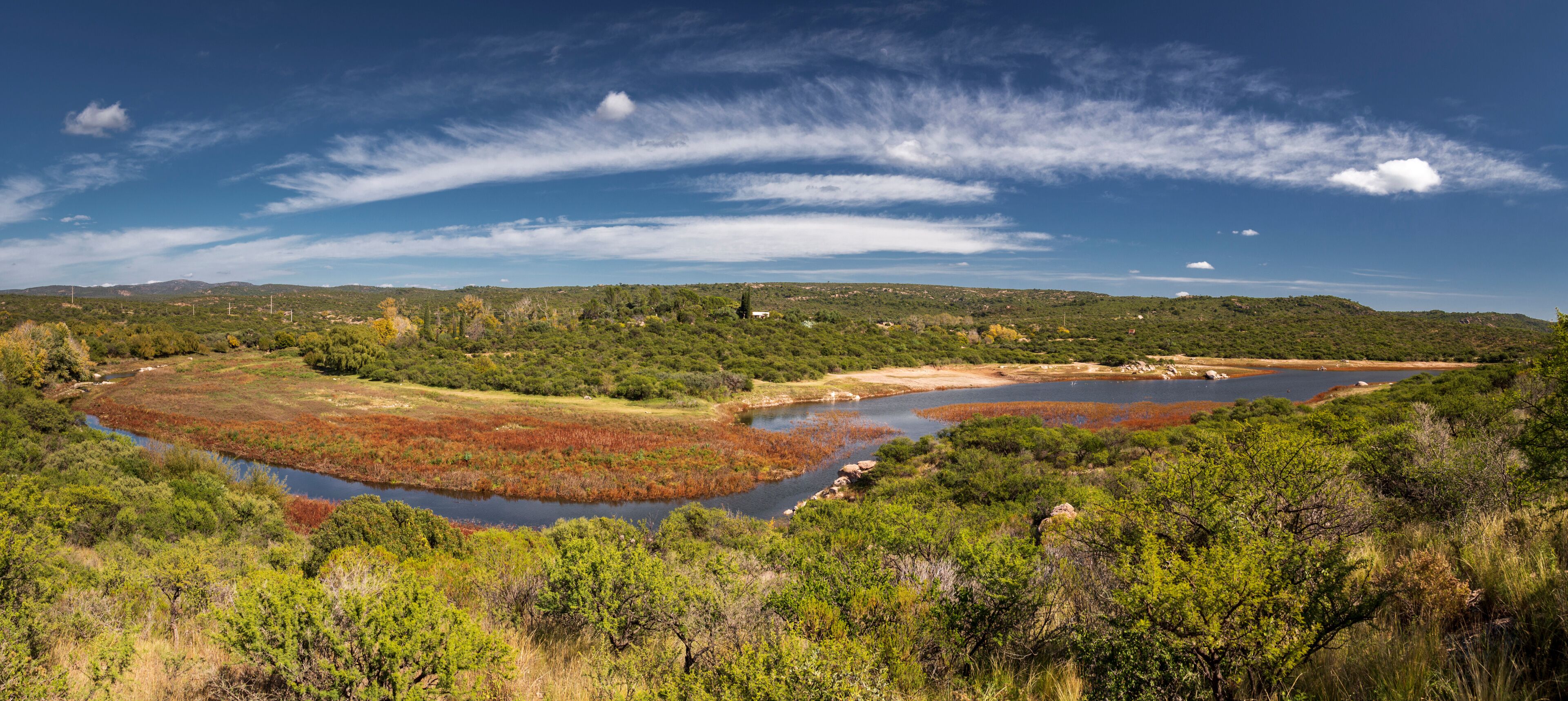 A coastal landscape with a river, marshy areas, and dense greenery.