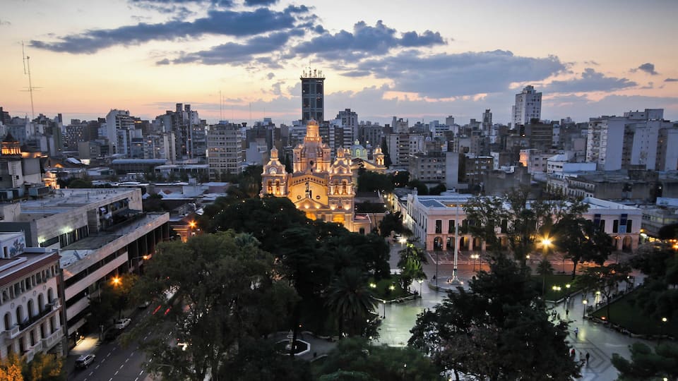 A cityscape at dusk with a prominent cathedral and surrounding buildings.