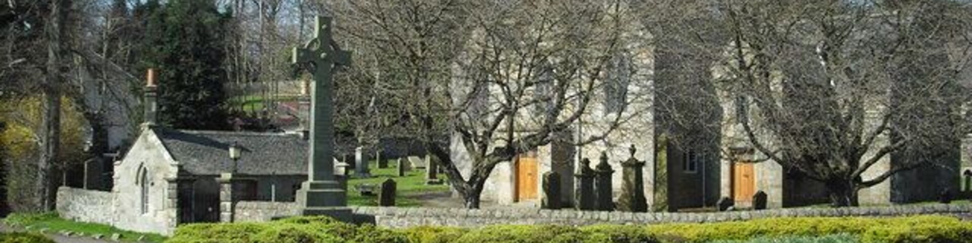 Un cementerio con lápidas, una iglesia y un monumento con una cruz.