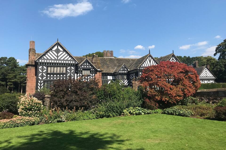 A Tudor-style building with a well-maintained garden and a clear blue sky.