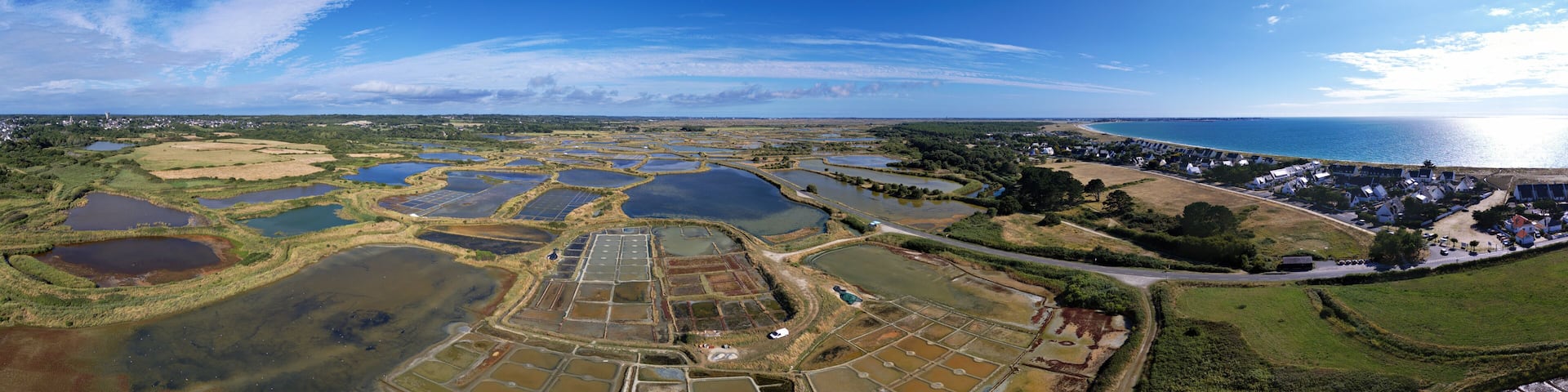 Panorama with sea salt marshes of Guerande, La Turballe with Pen Bron and Le Croisic with sea in the peninsula of Guerande, Brittany, France, drone photo