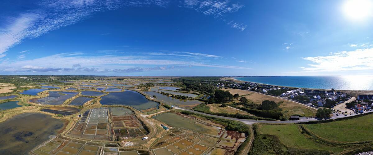 An aerial view of a coastal area with multiple water bodies, a residential zone, and a clear sky.